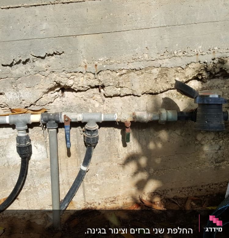 צינורות מים עם ברזים על קיר בטון